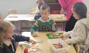Three children sitting at table doing crafts