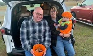 Pastor Eddite Thomas and his wife Sherry sitting on a tailgate with grandchild